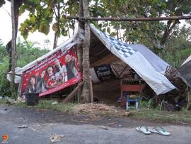 Tenda darurat yang terbuat dari terpal dan bekas spanduk didirikan di kebun sebagai tempat tingga...