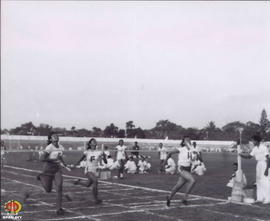 Tiga orang peseta lomba lari berebut melewati garis finish.