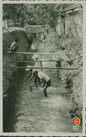 Para pekerja proyek sedang membersihkan selokan yang terletak di pinggiran rumah warga. Gambar di...